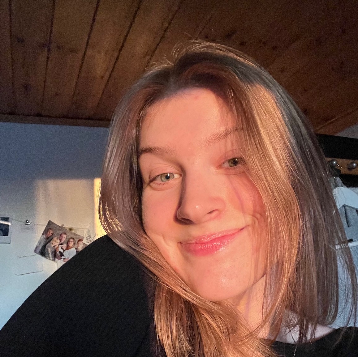 En ung tjej tittar in i kameran och ler.